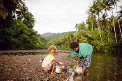 A woman cleans her pots in a river while her child watches. (Department of Foreign Affairs and Trade)  [flickr.com]  CC BY 
Información sobre la licencia en 'Verificación de las fuentes de la imagen'